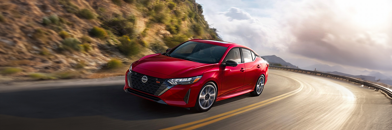 2024 Nissan Sentra in red taking a mountain curve at speed.