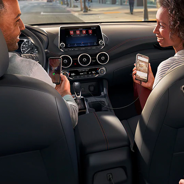 2024 Nissan Sentra interior with people using their smartphones to show device connectivity.