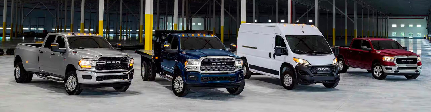 A lineup of four Ram Brand vehicles parked in an industrial garage.