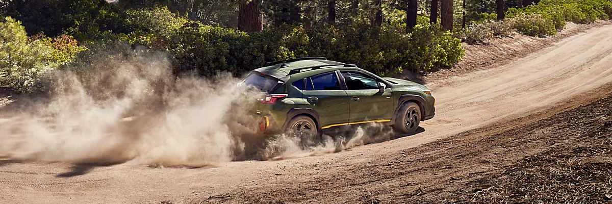 2024 Subaru compact SUV driving on dusty wooded trail