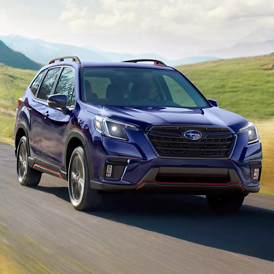 A blue 2024 Subaru Forester 5-seater SUV drives through the countryside