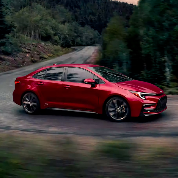 Hybrid SE AWD shown in Ruby Flare Pearl driving on a wooded street.