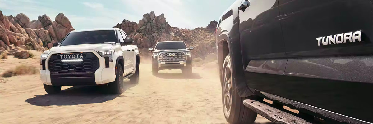 Group of 2024 Toyota Tundras driving through sand in daytime