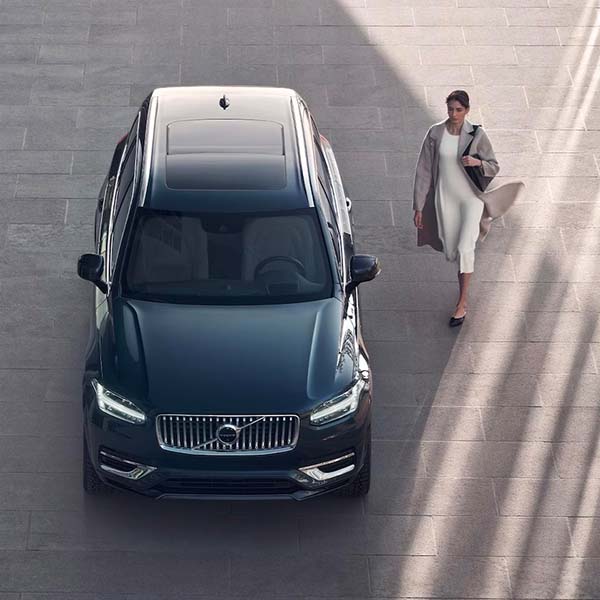 Exterior shot of a 2024 Volvo XC90 Recharge parked while a person walks up to the drivers side door.