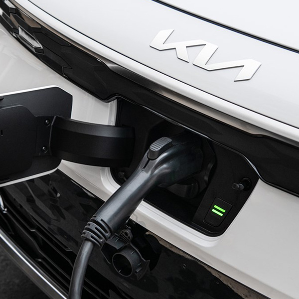 2025 Kia Niro EV being charged at a public station, close-up.