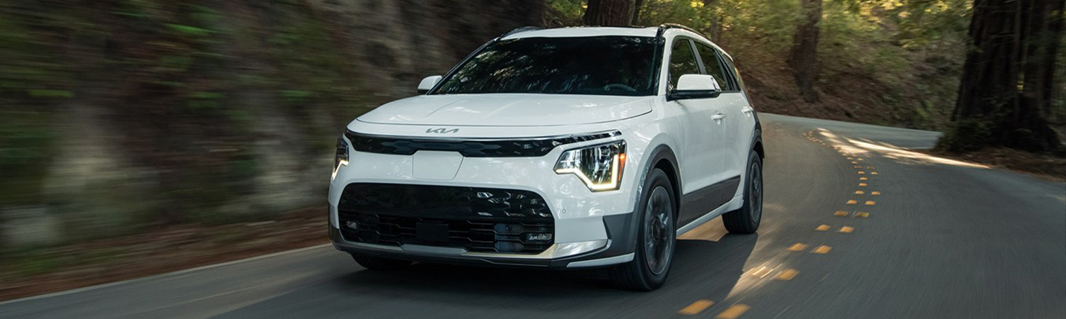 2025 Kia Niro EV driving fast down a forest road, front three-quarter view.