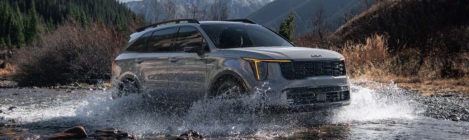 Grey 2025 Kia Sorento driving through a shallow stream.