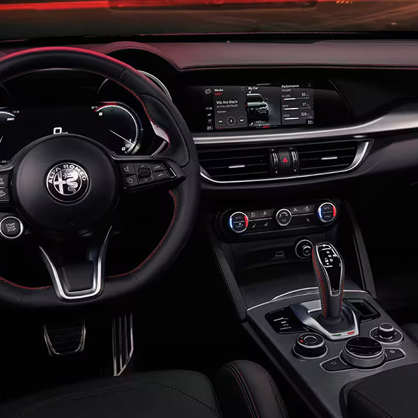 Interior view of the 2025 Alfa Romeo Stelvio dashboard featuring the steering wheel, touchscreen, and center console.