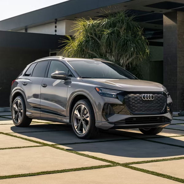 Three-quarter front view of the Audi Q4 e-tron parked in front of a modern home.