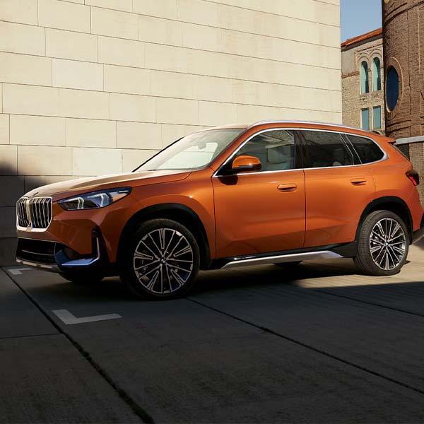 Orange 2025 BMW X1 parked on city street