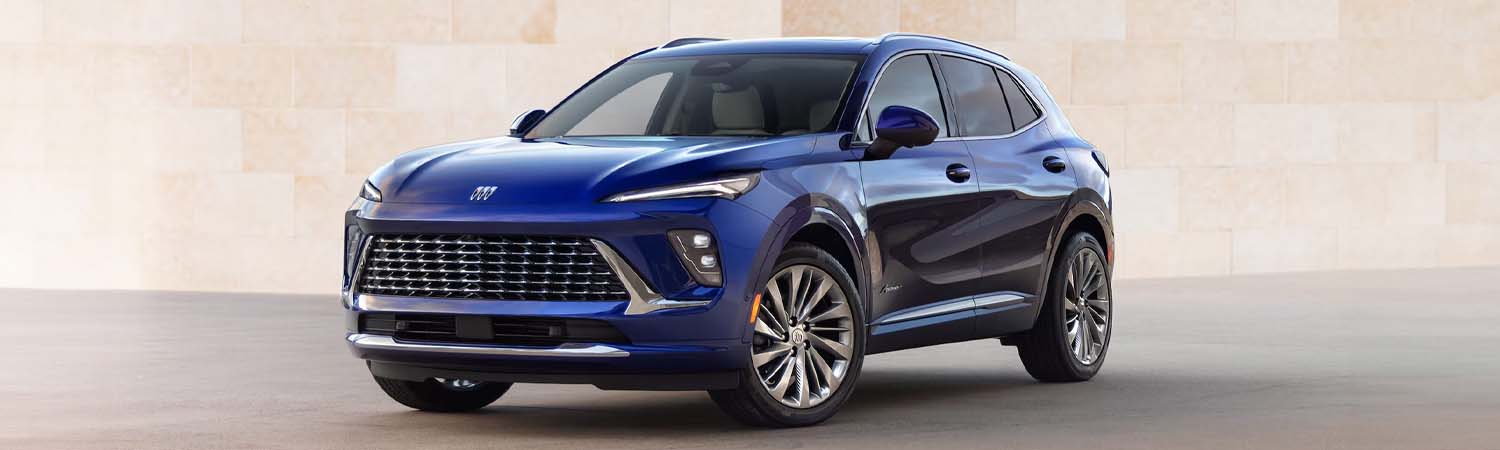 Blue 2025 Buick Evision parked in front of brick wall.