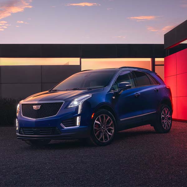 Blue 2025 Cadillac XT5 parked in front of modern residential building.