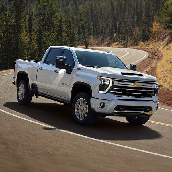 Side shot of the 2025 Chevrolet Silverado HD driving down winding road
