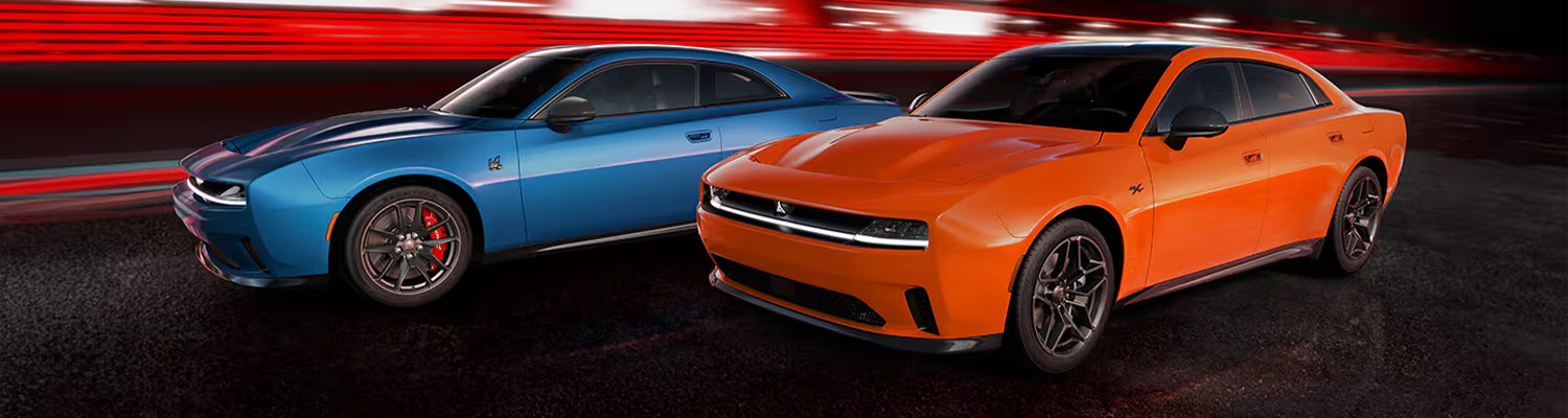 A blue 2024 Dodge Daytona Scat Pack BEV two-door and an orange 2024 Dodge Daytona R/T BEV four-door, parked side-by-side with the lighted background blurred.