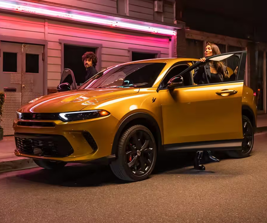 Two people getting out of a yellow Dodge Hornet