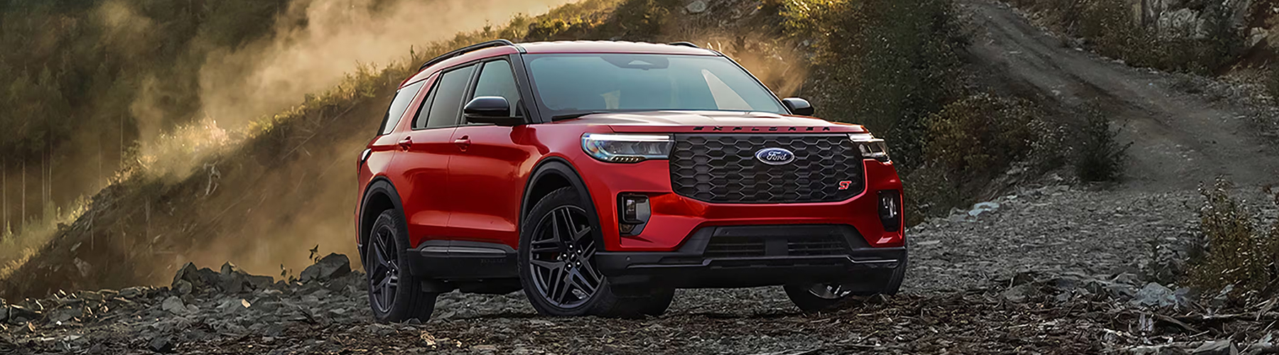 Red 2025 Ford Explorer® parked on gravel with a mountain forrest scape in the background