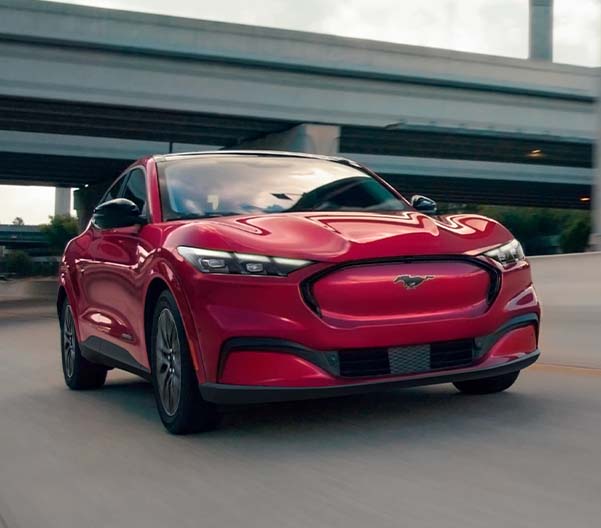 Red 2025 Ford Mustang Mach-E racing down a highway.