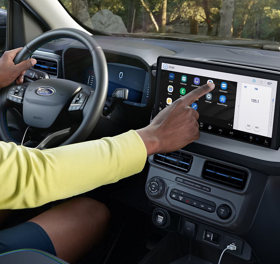 A driver using the touchscreen on a parked 2025 Ford Maverick® pickup