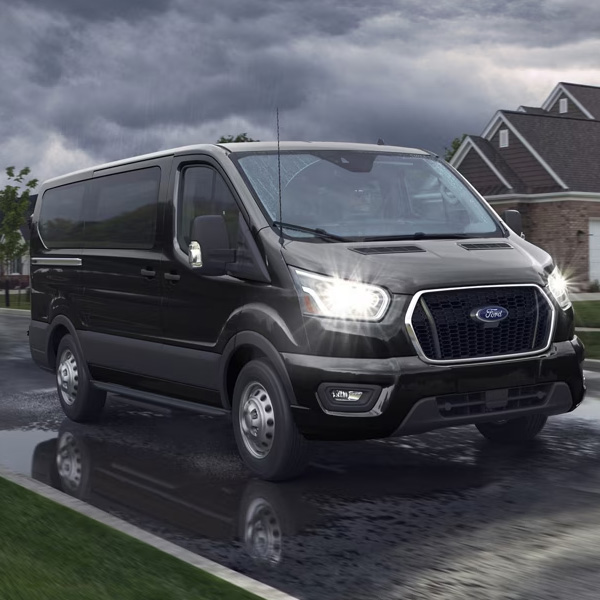 Black 2025 Ford Transit driving down residential street in the rain