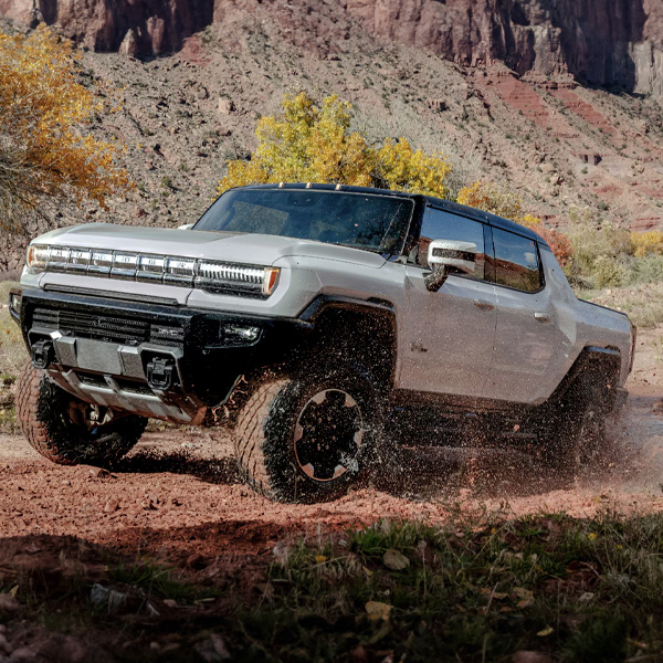 Silver 2025 GMC HUMMER EV Pickup driving off-road.