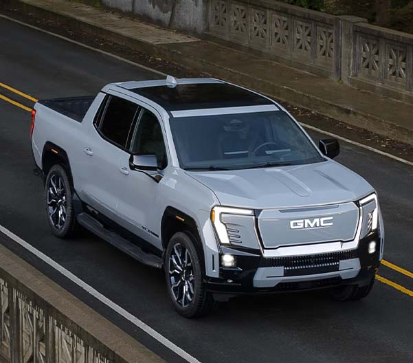 Silver blue 2025 GMC Sierra EV parked along a highway road