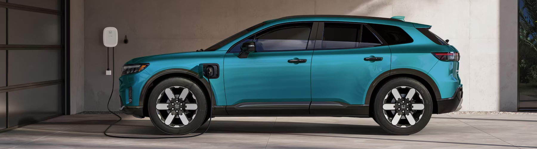 2025 Honda Prologue Elite shown in North Shore Pearl, parked at home and charging with the Honda Home Charger.