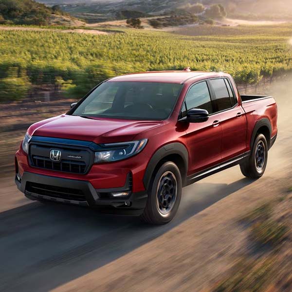Red 2025 Honda Ridgeline driving through vineyard