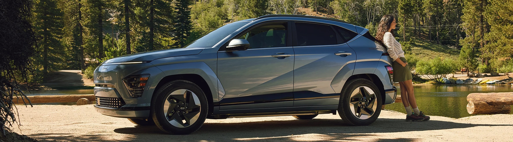 A woman relaxes - 2025 Kona Electric parked.