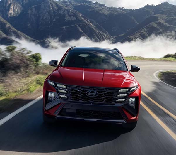 Red 2025 Hyundai Tucson Hybrid racing down a mountainous road