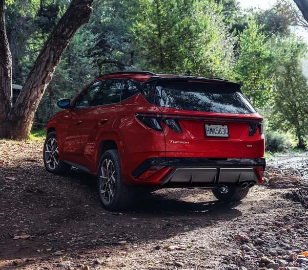 Red 2025 Hyundai Tucson Hybrid parked on a rural dirt road