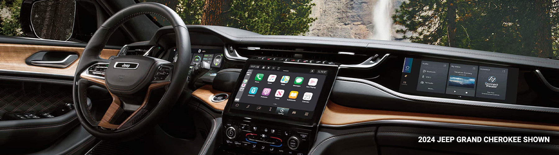 Display The interior of a 2024 Jeep Grand Cherokee Summit Reserve focusing on the steering wheel, Uconnect touchscreen, center stack and front passenger touchscreen.