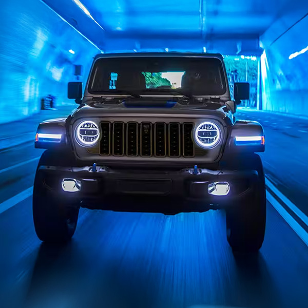 2025 Jeep Wrangler 4xe 4xe front view with headlights on in blue lit tunnel 