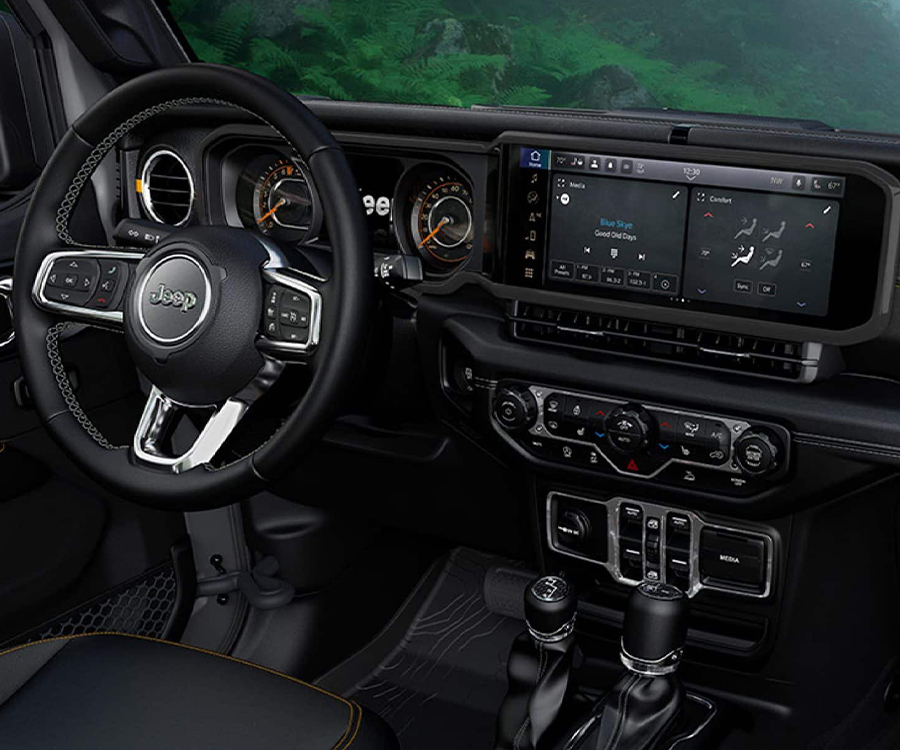 Display The front row in the 2025 Jeep Wrangler focusing on the steering wheel, Uconnect touchscreen and dash.