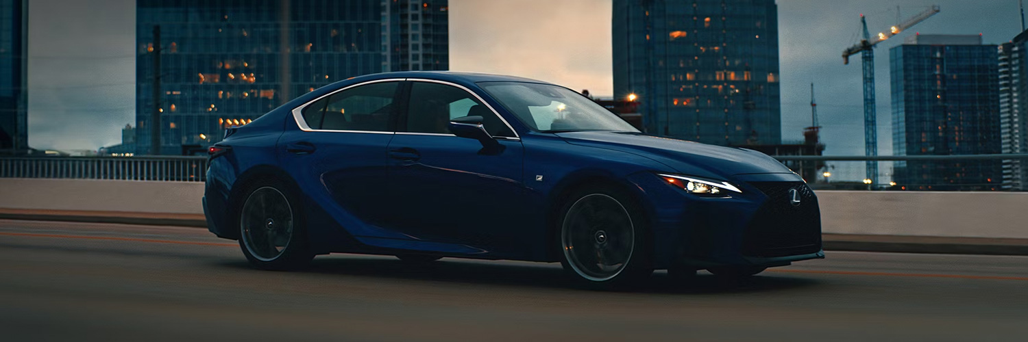 Side profile shot of the 2025 Lexus IS driving down city highway