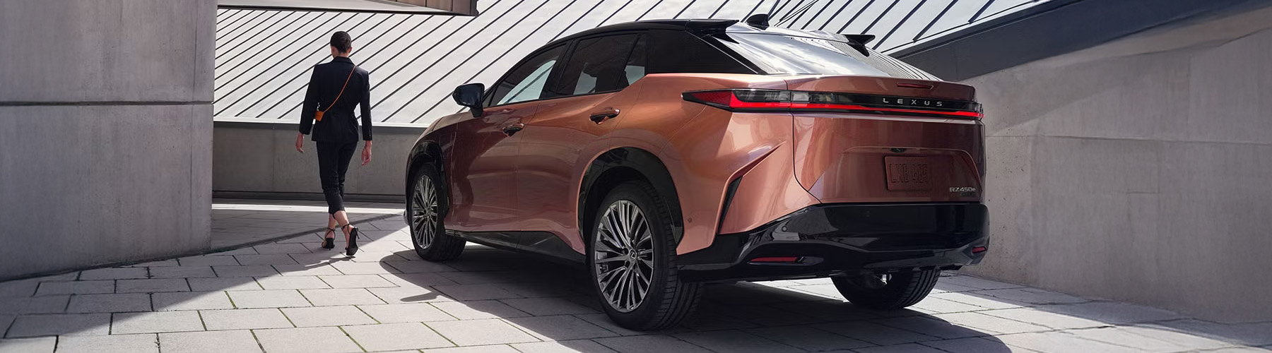 A woman is walking beside the RZ 450e shown in Copper Crest and Black Onyx.
