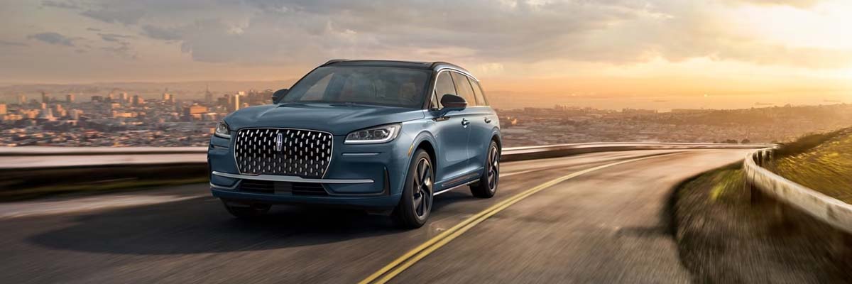 Image of the 2025 Lincoln Corsair driving along a road with a cityscape in the background