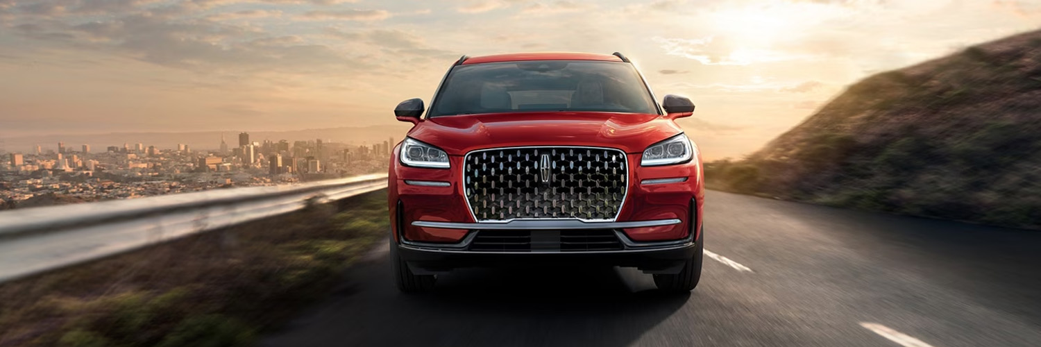 2025 Lincoln Corsair® SUV is being driven on a mountain road with a city in the background