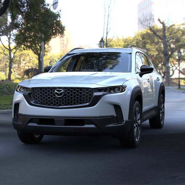 A white 2025 MAZDA CX-50 Hybrid racing down a street.