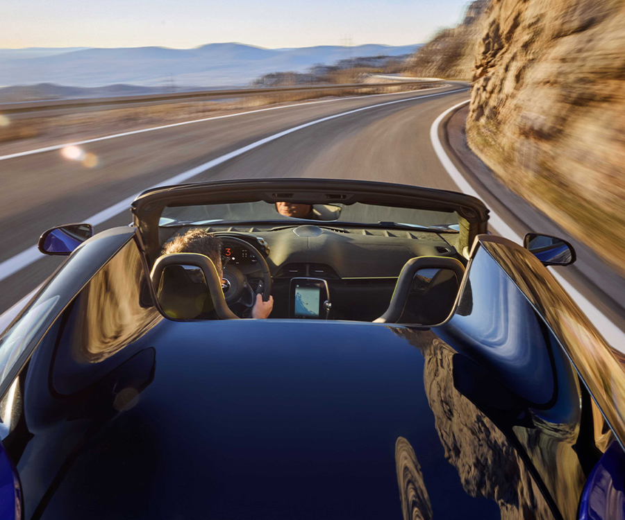 2025 McLaren Artura Spider driving full speed on mountain highway road