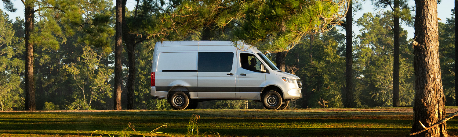 Side profile shot of the 2025 Mercedes-Benz Sprinter Crew parked in wooded area