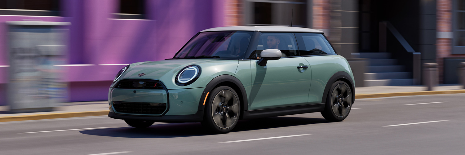 Front 3/4 shot of the 2025 MINI Cooper Hardtop 2 Door driving down city street.
