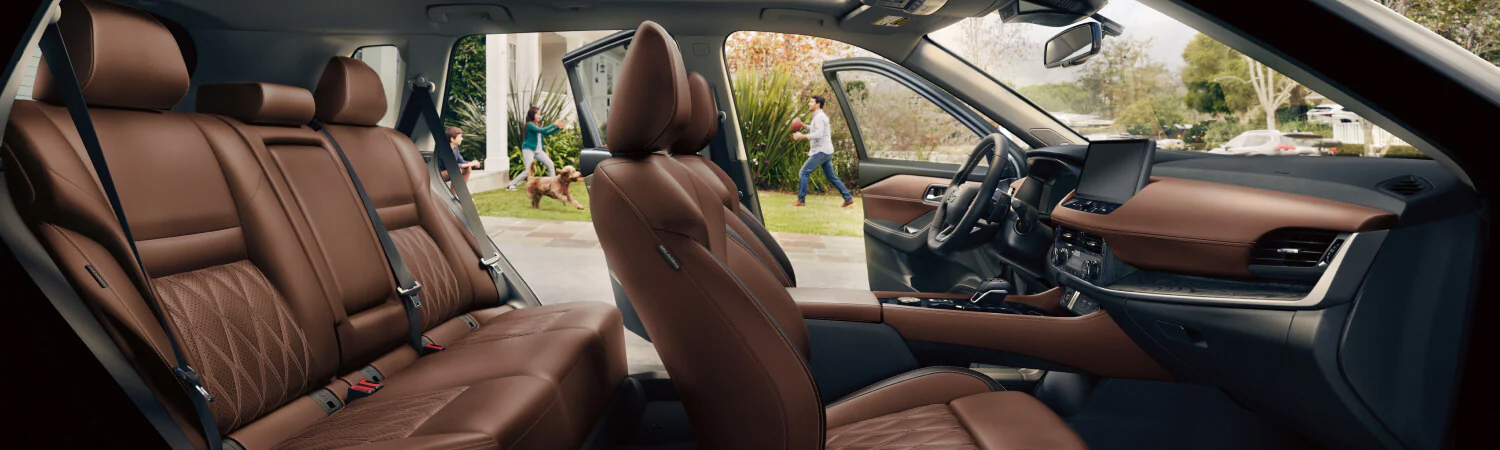 2025 Nissan Rogue view of cabin with all doors open, showing seats and a family playing with their dog in the background