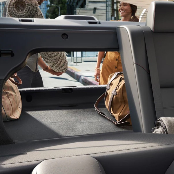 2025 Nissan Sentra displaying people putting a rug into the cargo space with one of the 60/40 split rear seats up and one down.