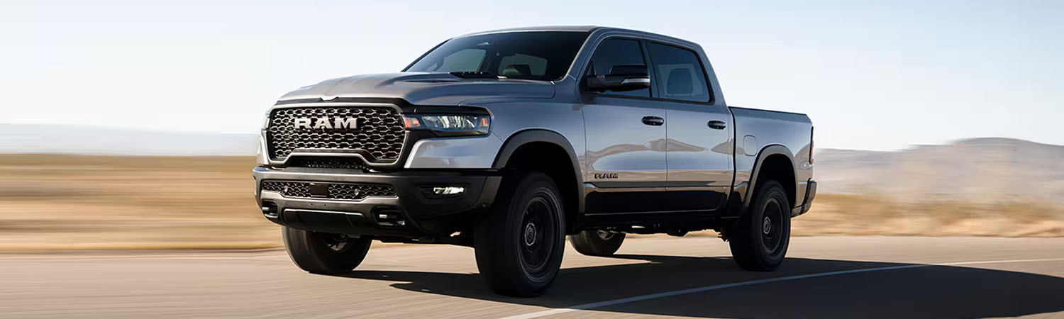 A silver 2025 Ram 1500 Rebel crew cab being driven off-road in the woods.