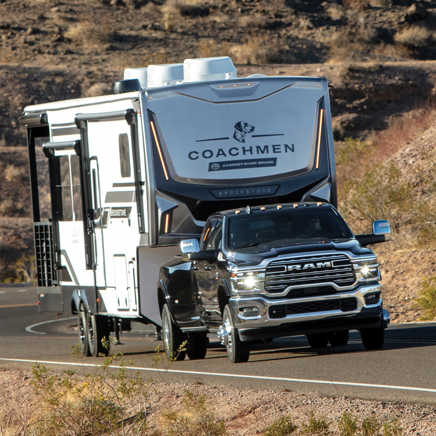 A black Ram 3500 Limited Longhorn 4x4 Crew Cab traveling down a mountain highway as it tows a fifth-wheel travel trailer.