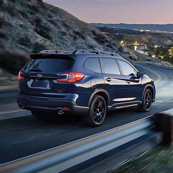 Rear 3/4 shot of the 2025 Subaru Ascent driving down winding road