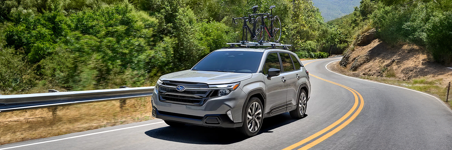 The 2025 Subaru Forester driving along a bend with a bicycle roof rack