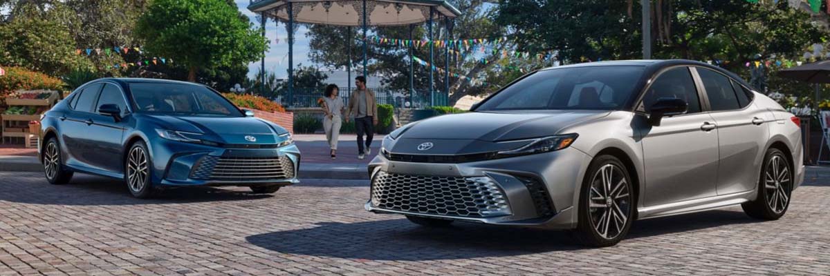 Two 2025 Toyota Camrys side by side parked in front of a park