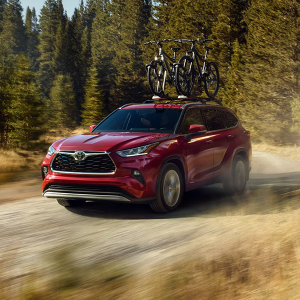 Hybrid Platinum shown in Ruby Flare Pearl driving through the woods with a bike rack on top.