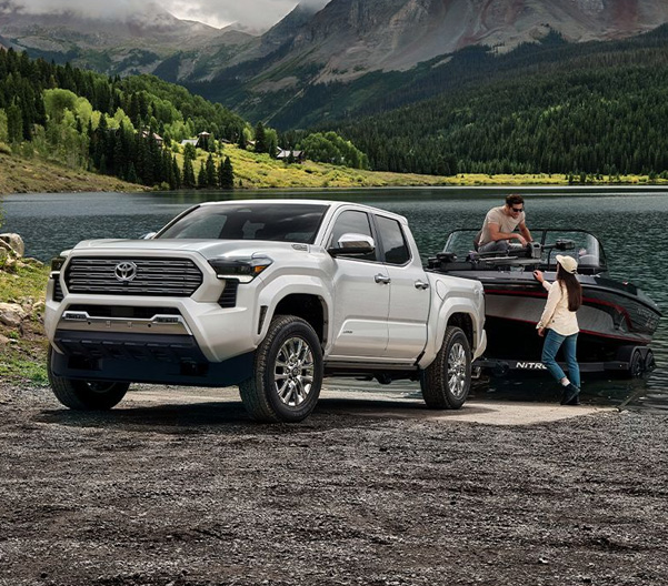 2025 Toyota Tacoma Limited shown in Wind Chill Pearl towing a boat